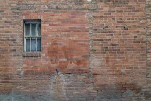 urban texture and background - grunge brick wall with a small, neglected window photo