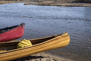 a bow of beautiful, home built, wooden canoe on a river shore photo