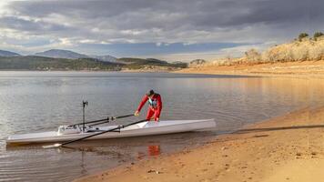 mayor remero es aparejo su remo cáscara en un apuntalar de carretero lago en del Norte Colorado en invierno paisaje foto