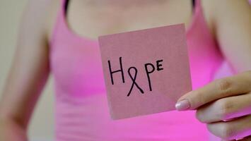 Breast Cancer Awarness Month. Inscription hope on pink streaker in female hand close-up. photo