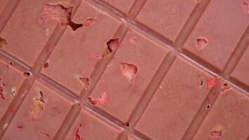 A bar of pink ruby chocolate with freeze-dried strawberries and almonds close-up. A healthy dessert based on berries and nuts photo