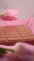 A bar of pink ruby chocolate with sublimated freeze-dried strawberries and almonds and spring tulip flowers . A dessert based on berries and nuts for International Women's Day, March 8, mother's day photo