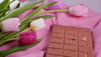 un bar de rosado rubí chocolate con sublimado liofilizado fresas y Almendras y primavera tulipán flores . un postre establecido en bayas y nueces para internacional De las mujeres día, marzo 8, de la madre día foto