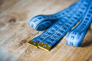 Blue measuring tape on wooden table. Tailor concept. Close-up. photo