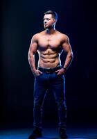 Bodybuilder posing on black background. Muscular and fit young bodybuilder fitness male model posing over dark background. Full size portrait. photo