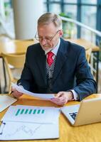 Thoughtful businessman is reading important business papers. Photo in front of the window with city view. Business process concept