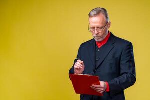 Middle aged businessman standing and holding file folder. Horizontal format isolated on yellow background. photo