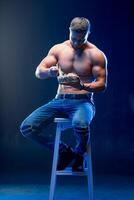 joven muscular hombre participación sano alimento. dieta y sano comiendo concepto. desnudo torso atleta en un silla. foto