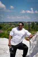 Handsome athletic man in white shirt standing outdoor. Strong big man in sunglasses outdoor. photo