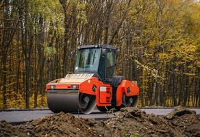 Road repair, compactor lays asphalt. Heavy special machines. Asphalt paver in operation. Side view. Closeup. photo