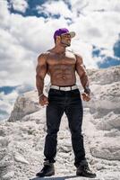 Strong healthy shirtless man. Muscular young bodybuilder with naked torso standing on landscapes. photo