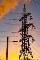 Electricity pylons against orange and yellow sunset. Energy distribution network. Selective focus. photo