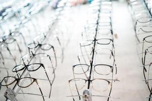 exposición de lentes a estantes. de moda gafas mostrado en un pared a el óptico tienda. de cerca. foto