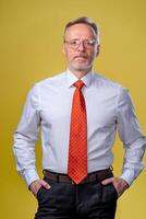 Content senior business man in shirt and vest. Posing in studio on yellow background. Confident. Business style concept photo