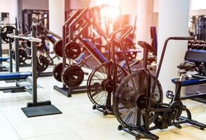 Fitness hall with sport bikes. Metal bicycle trainers, equipment in gym. photo