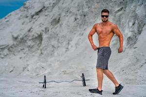 Fit athletic man working out outdoor. Handsome young bodybuilder with naked torso. photo