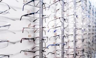 Row of glasses at an opticians. Eyeglasses shop. Stand with glasses in the store of optics. Showcase with spectacles in modern ophthalmic store. Closeup. photo