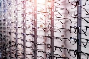 Row of glasses at an opticians. Eyeglasses shop. Stand with glasses in the store of optics. Showcase with spectacles in modern ophthalmic store. Closeup. photo