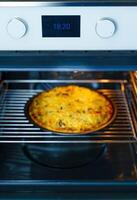 Pizza cooking on a round tray in a gas oven. Pizza with cheese on a round tray in an oven. Homemade photo