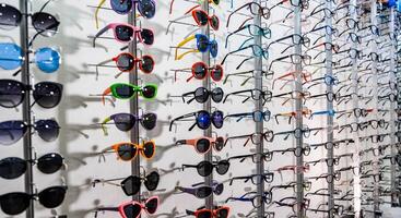 Exhibitor of glasses consisting of shelves of fashionable glasses shown on a wall at the optical shop. Optics, health care and vision concept close up of eyeglasses at optician photo