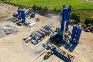 Equipment for production of asphalt, cement and concrete. Concrete plant. High tower of an asphalt plant. Harmful production. A mixture of bitumen and gravel, a mix machine. Aerial view. photo