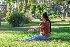 Woman is doing yoga asana outside in a park. Concept of balancing and healthy lifestyle. photo