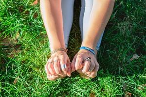 cerca arriba manos y piernas de mujer haciendo yoga ejercicio en un césped en un parque. concepto de sano estilo de vida. foto