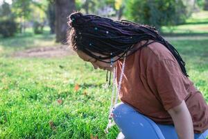 Young European woman is sitting on a grass and doing yoga exercise. Healthy lifestyle outdoors. photo