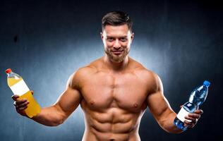 Sexy sportsman holding a bottle of water and soda. Choosing between healthy and harmful drink. Portrait. Looking at camera. Closeup photo