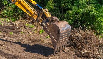 amarillo retroexcavadora con hidráulico pistón brazo. pesado máquina para excavación en construcción sitio. foto