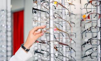 Row of glasses at an opticians. Eyeglasses shop. Stand with glasses in the store of optics. Showcase with spectacles in modern ophthalmic store. Closeup. photo