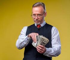 Man holding lots of dollar bills in hands, isolated on yellow background. Happy man enjoying money. Hands with money. Rich with success. Positive emotion facial expression feelings. photo