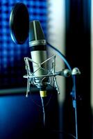Close up studio condenser microphone with pop filter and anti-vibration mount live recording with color lights background. Side view photo