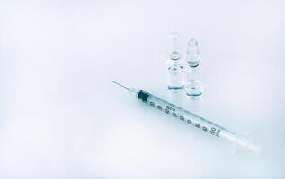 a syringe with a needle is near two vials with an injection of beauty on a white surface in a beauty salon. Close-up photo