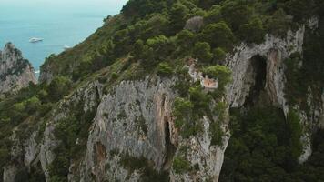 maestoso scogliere Torre al di sopra di tranquillo azzurro mare acque. donna su punto di vista prospiciente capri isola con sereno oceano vista. estate Italia paesaggio. video