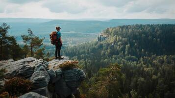 AI generated Hiker Stands on Rocky Cliff Overlooking Vast Lush Forest photo