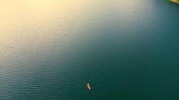 aéreo Visão solitário barco em uma tranquilo lago, uma solitário barco flutua em a calma superfície do uma grande lago. video