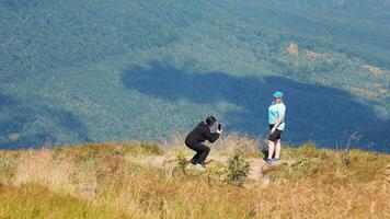 Foto Session im das Berge. Touristen sind fotografiert gegen das Hintergrund von Berg Landschaften. ein Person erfasst ein Foto von ein Begleiter gegen das Hintergrund von üppig Berg Grün. video