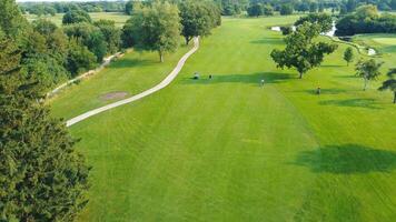 szenisch Golf Kurs Antenne Perspektive, üppig Grün Golf Kurs mit Golfer und Wege unter klar Himmel. video