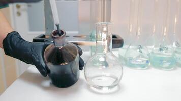 Laboratory Flask Transfer Experiment, Hand in glove pouring liquid between flasks in lab video