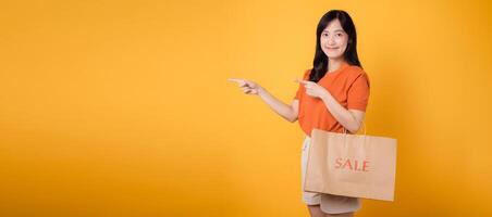 Attractive asian female buyer highlights her stylish purchases during a sale, adding a touch of glamour to her shopping experience. photo