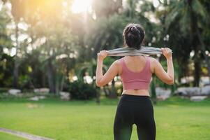 unirse el contento y ajuste viaje de un 30s asiático mujer vistiendo rosado ropa de deporte como ella calienta abajo después un puesta de sol correr en un público parque. abrazo bienestar vivo y conectar con naturaleza. foto