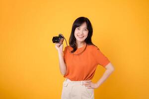 Joyful woman traveler ready for a journey with a camera and positive holiday spirit. isolated on yellow background photo