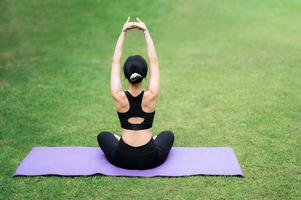 retrato ajuste joven 30s asiático mujer en rosado ropa de deporte con yoga estera. extensión músculos en parque. mejorar salud y vitalidad mediante yoga práctica. conectar con naturaleza para sereno foto