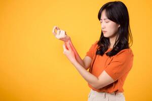 Woman wrist pain due to arthritis showcased in yellow studio portrait. Concept of injury and physical discomfort. photo