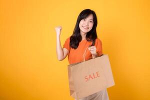 Get ready to celebrate the joy of love and incredible deals Young woman exudes happiness while showcasing her purchases isolated on yellow background, embodying the spirit of shopping excitement. photo