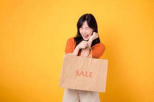 Embrace the surprise of unbeatable deals while shopping. Happy young woman showcases her purchases, reflecting the joy of discovering exciting bargains. isolated on yellow background. photo