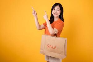 Trendy asian woman shopper choosing fashion pieces with a joyful smile, making the most of a sale event. Stylish purchases. photo