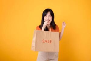 surprise of best deals while shopping Trendy woman showcases her joyful purchases isolated on yellow background, reflecting the excitement of savvy shopping. photo