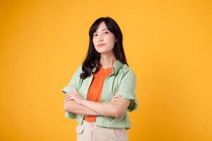 Radiate confidence portrait of young Asian woman wears pastel green shirt on orange shirt confidently crossing her arms. Perfect for capturing a sense of self assurance and empowerment. photo